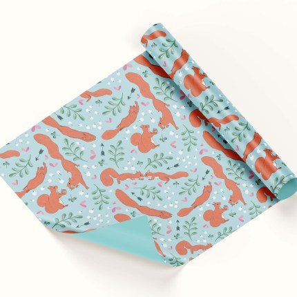 A wrapping paper roll featuring a seamless pattern. The pattern tells the story of two red squirrels falling in love, with clover, baby's breath flowers, arrows, leaves and hearts strewn around them. It has a light blue background.