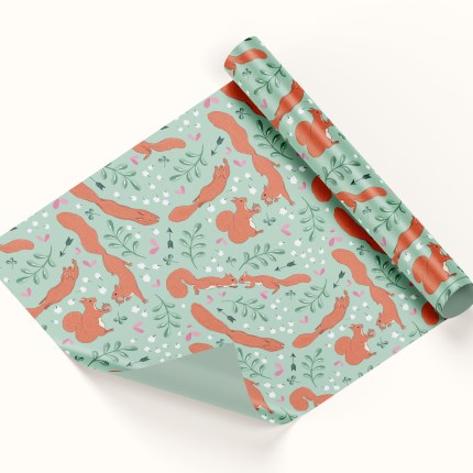 Green wrapping paper mockup with red squirrels over it, showing a pair of red squirrels and their love story, featuring little hearts, arrows, baby's breath flowers and clover